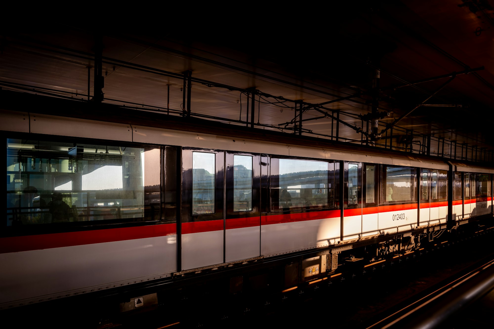 A metro train at a station, lit by low sun